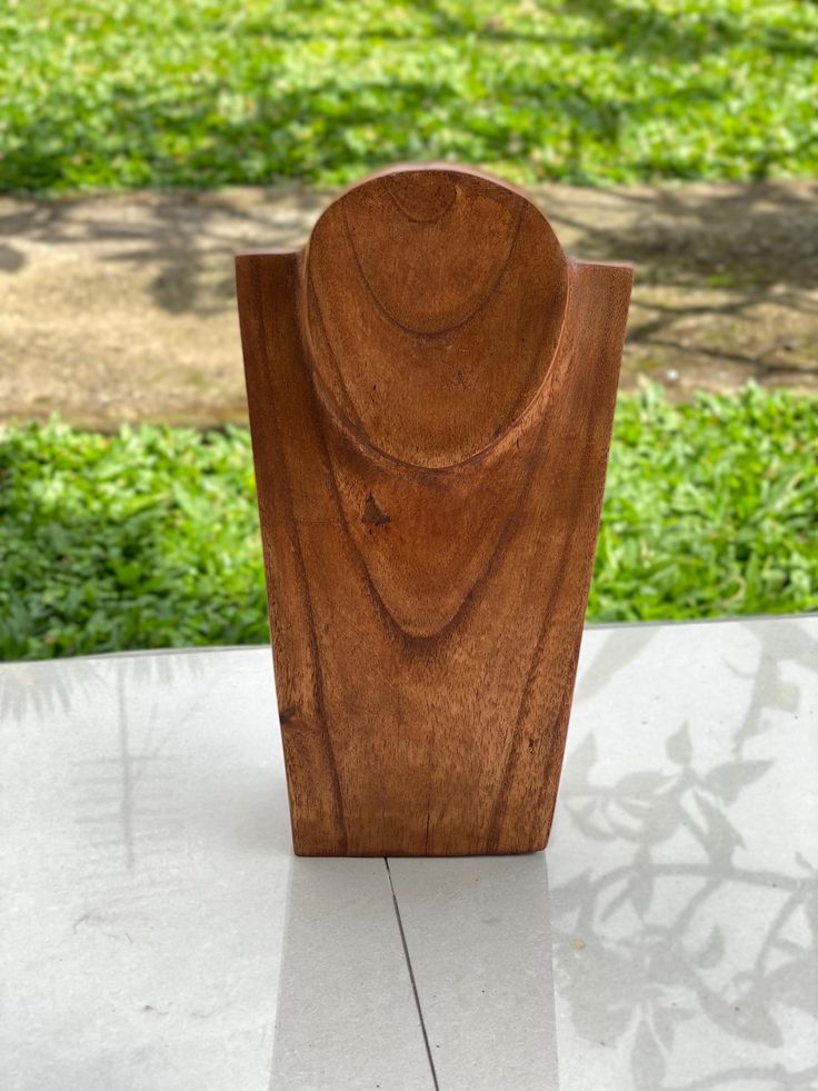 a wooden sculpture sitting on top of a white tile floor in front of green grass