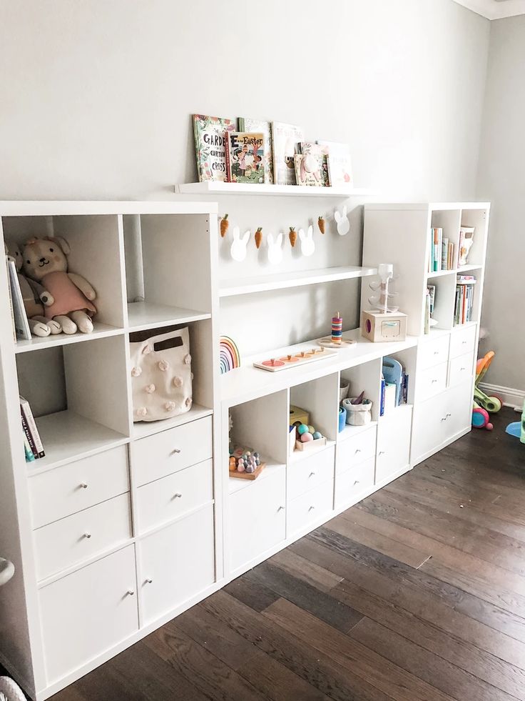 a white bookcase filled with lots of books next to a wall mounted teddy bear