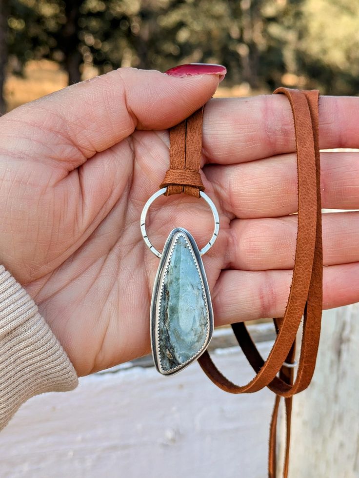 Combining three of my favorite materials! Silver, Stone & Leather :) This unique necklace features a beautiful ombre green-grey stone, anchored in solid Sterling Silver.  The necklace is fully adjustable, wear it short, choker style, or very long low-chest level, or anywhere in between!  Adjust simply by moving the silver slider. All the metal on the necklace is solid Sterling Silver and forged by hand, and features hand stamped and oxidized designs. The leather is genuine, super soft Deerskin leather, in a warm brown.  This leather is buttery smooth and feels amazing against your skin! This necklace is a large statement style piece, but it is lightweight, for all day comfort.  This will look beautiful with all your western or boho outfits.   The last four photos show more of my hand forge Handmade Adjustable Moss Agate Necklace, Adjustable Artisan Moss Agate Jewelry, Adjustable Moss Agate Artisan Jewelry, Adjustable Moss Agate Gemstone Jewelry, Adjustable Jewelry With Natural Stones For Everyday, Bohemian Necklace With Large Adjustable Stone, Adjustable Labradorite Cord Jewelry, Adjustable Cord Labradorite Jewelry, Adjustable Everyday Pendant Jewelry