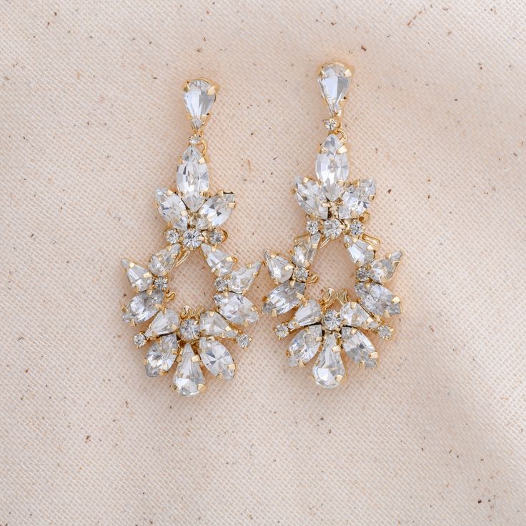 two pairs of gold tone earrings with clear crystal stones on the bottom and back of each ear