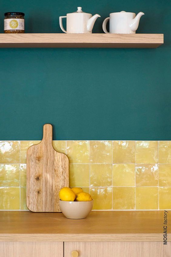 a wooden cutting board sitting on top of a counter next to a bowl of lemons