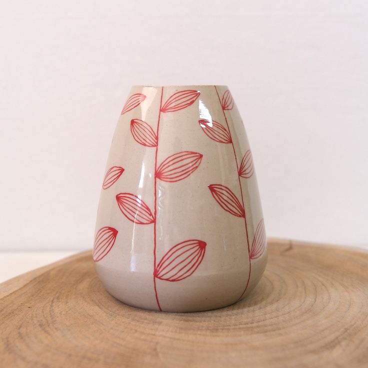 a white and red vase sitting on top of a wooden table