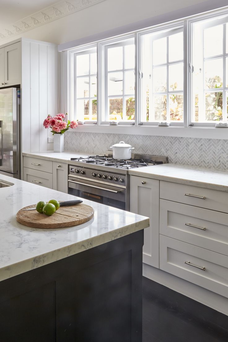 a kitchen with white cabinets and marble counter tops, an island in the middle has fruit on it