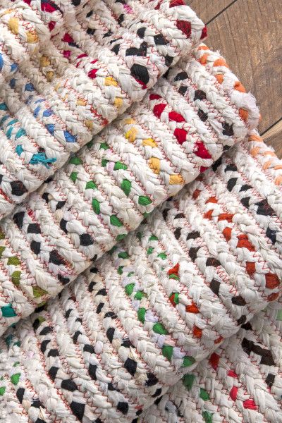 multicolored crocheted blanket laying on wooden floor next to white and black rug