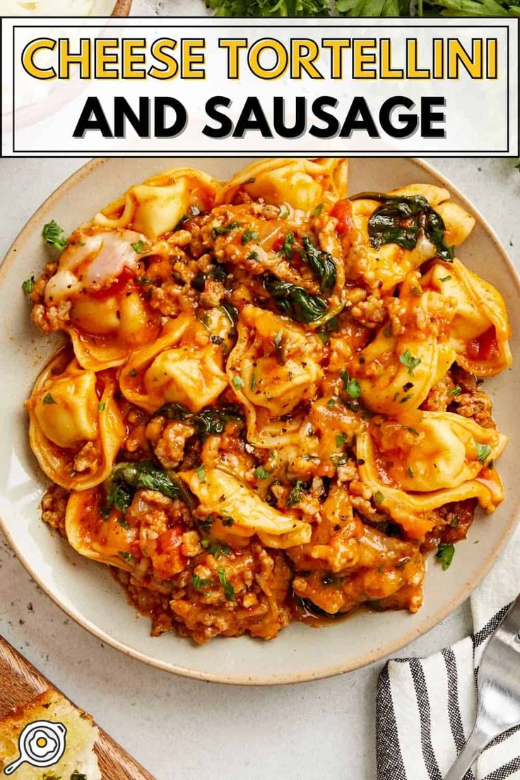 a white plate topped with tortellini and sausage next to bread on a table