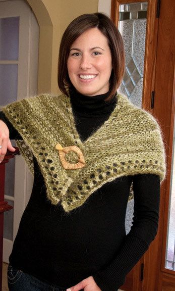 a woman wearing a green knitted shawl with a heart on the front and side