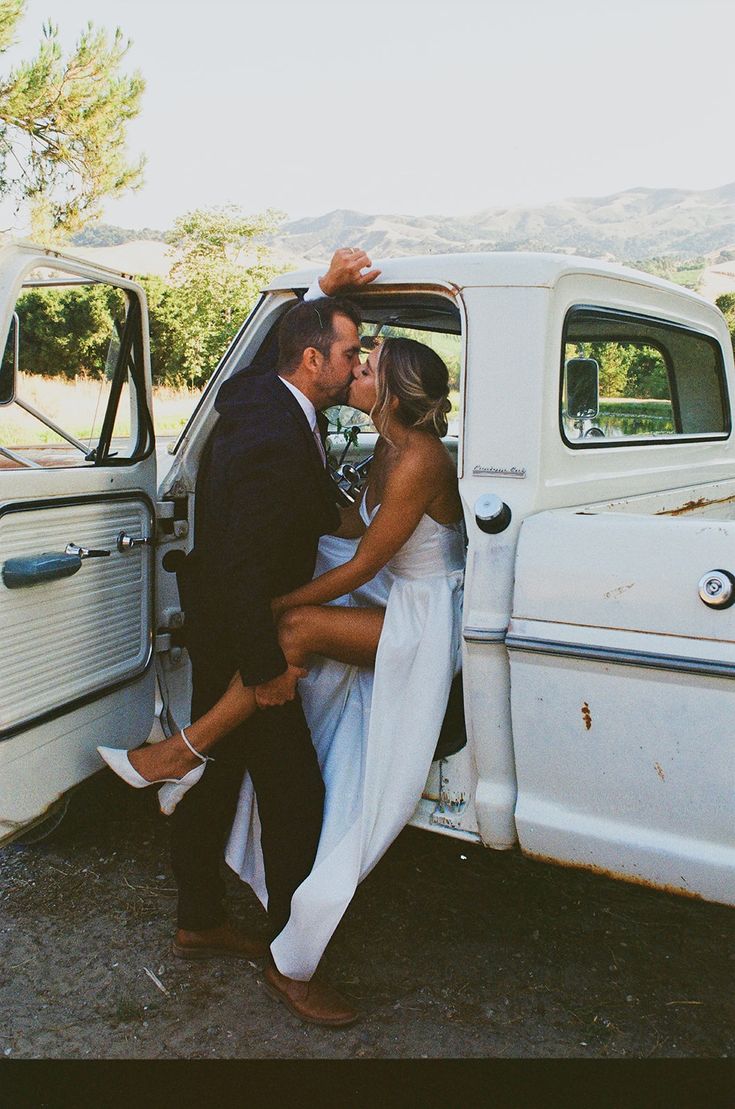 a man and woman kissing in the back of a white truck