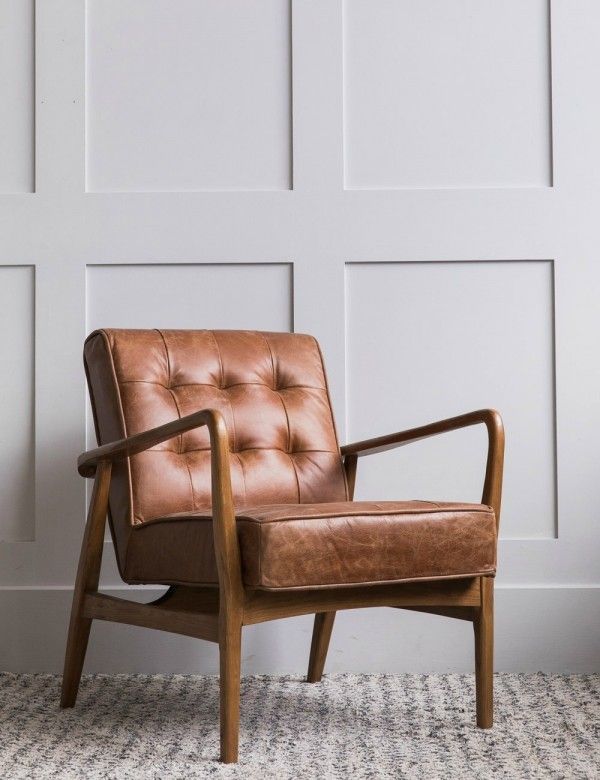 a brown leather chair sitting in front of a white wall