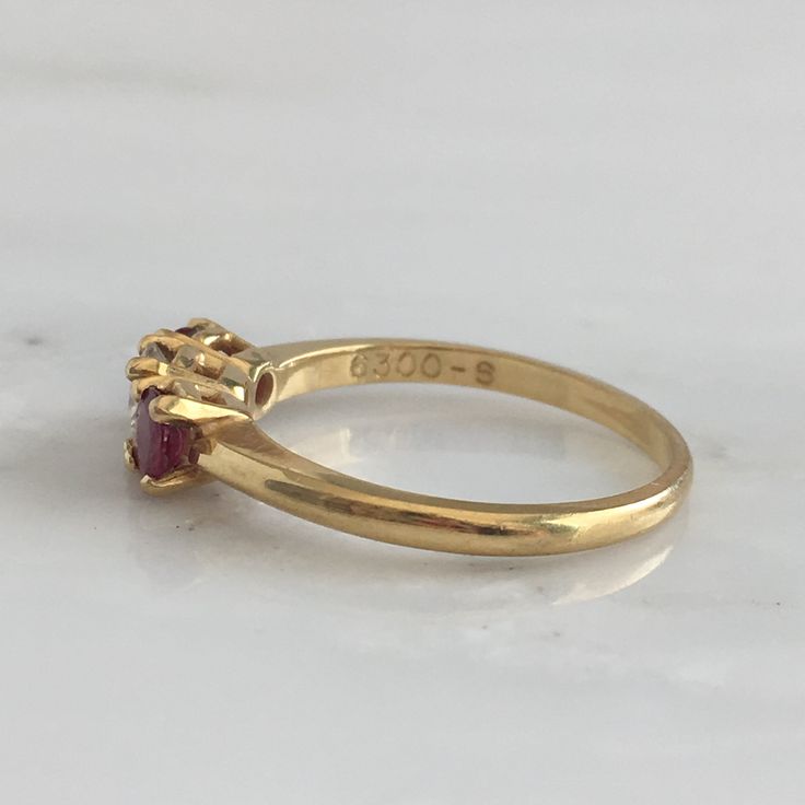 Details: Lovely Mid Century 18K yellow gold diamond and ruby ring, with two rubies and a diamond. Please ask all necessary questions prior to placing an order. Measurements: The size is 5 3/4 US and can be sized for a fee. Condition: The overall all condition of this ring is very good. Luxury Three Stone Ruby Ring, Classic Three-stone Ruby Ring, Classic Three Stone Ruby Ring, Classic Three Stone Ruby Ring In Yellow Gold, Classic Yellow Gold Three Stone Ruby Ring, Classic Ruby Ring With Single Cut Diamonds, Classic Three Stone Yellow Gold Ruby Ring, Classic Three Stone Ruby Ring With Diamonds, Formal Oval Ruby Ring With Single Cut Diamonds