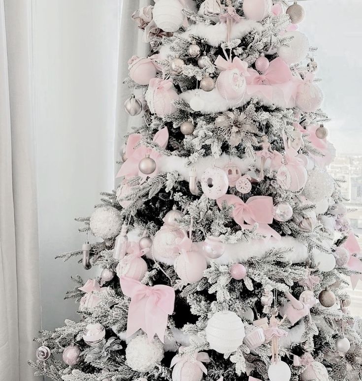 a white christmas tree decorated with pink and silver ornaments