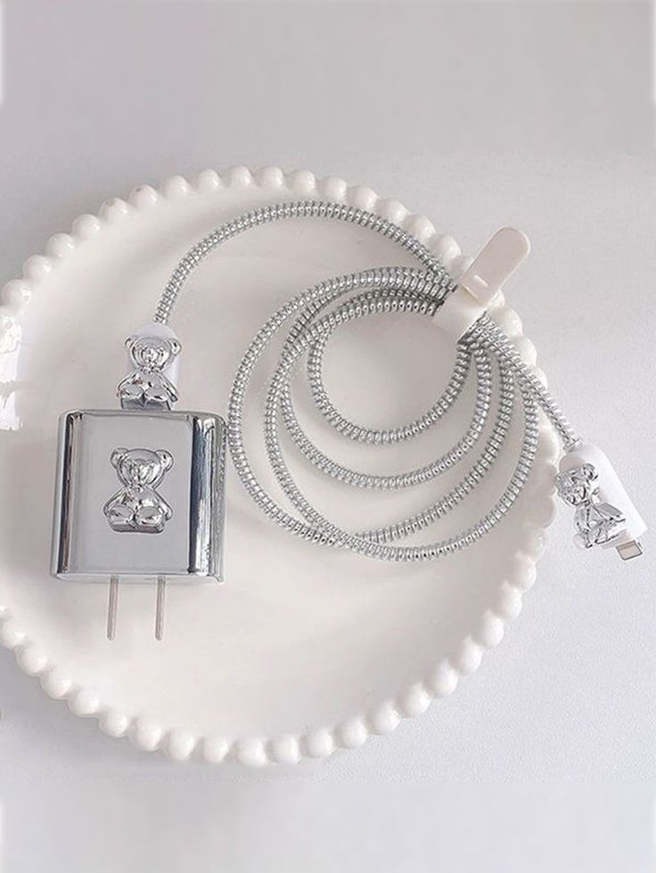 a white beaded necklace with a cell phone attached to it on a platter