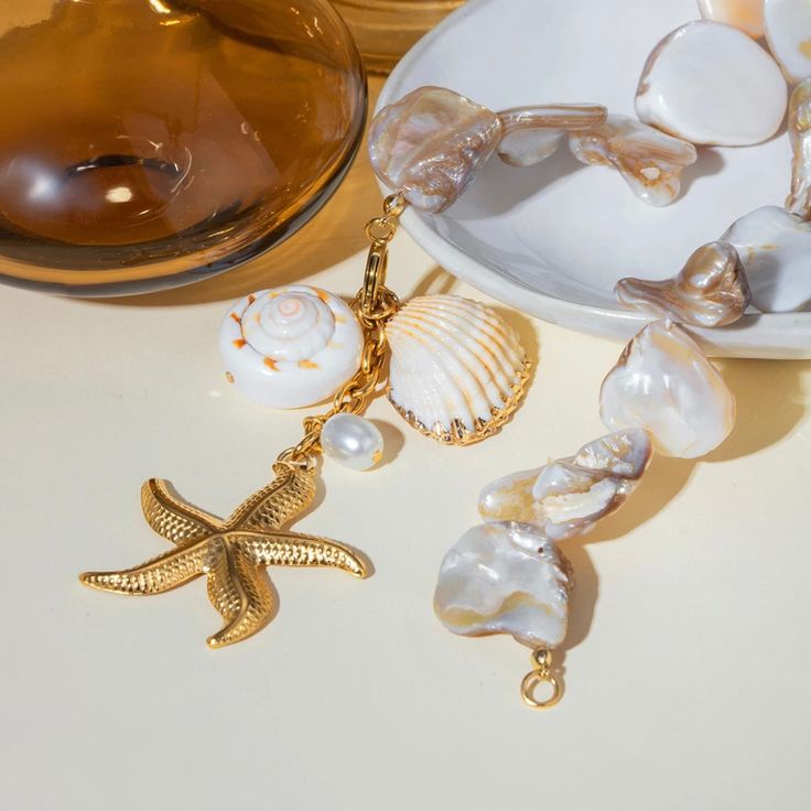 Introducing the Ocean Shell Necklace - a stunning piece that captures the beauty of the ocean and brings it into your everyday life. Made from natural shells, this necklace will transport you to a forever summer, filled with romantic walks on the beach. Add a touch of the ocean to your style with this elegant and unique necklace. Made to last! Tarnish and Water Resistant, Hypoallergenic 17" long Closure : Frontr Clasp 18k Gold PVD Plated over 316L Stainless Steel base / Natural Shells Beachy Strand Jewelry For Beach Party, Beach Party Beachy Strand Jewelry, Elegant Pearl Charm Shell Necklace For Beach, Ocean-inspired Pearl Charm Necklace For Vacation, Ocean-inspired Jewelry For Vacation, Ocean-inspired Jewelry For Beach Party, Ocean-inspired Strand Jewelry For Beach Party, Bohemian Pearl Charm Jewelry For Vacation, Bohemian Necklace With Pearl Charm For Vacation