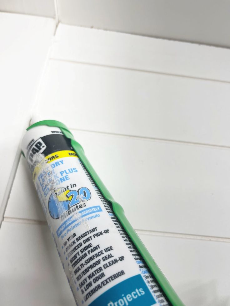 a tube of glue sitting on top of a white tile floor next to a wall