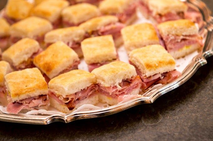 a platter filled with cut up sandwiches on top of a table