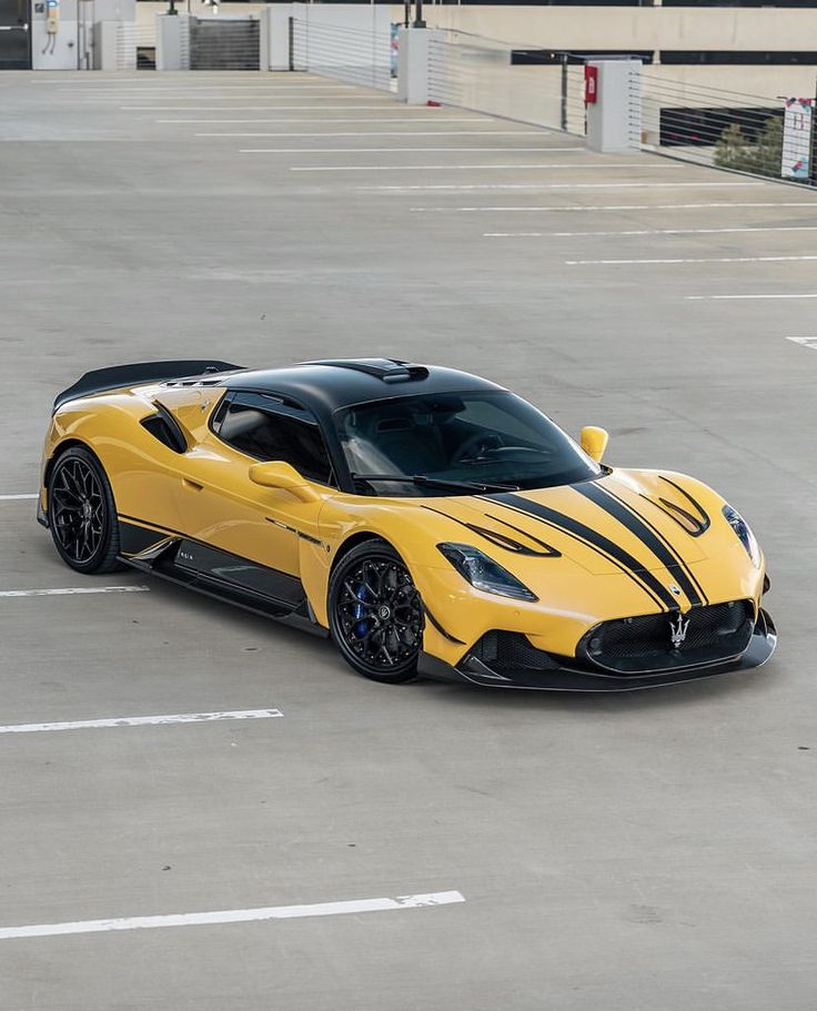 a yellow sports car parked in a parking lot next to an empty space with no people