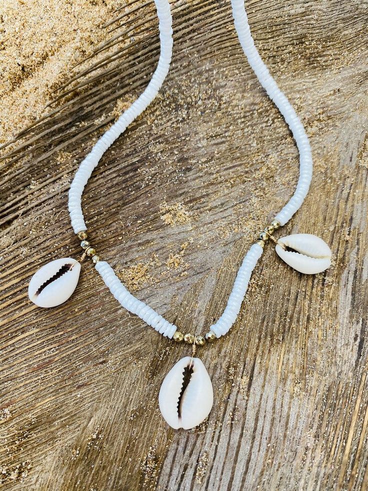 All About Cowrie Shells Necklace. Inspired by the beautiful Cowry Shells of Puerto Rico and Virgin Island beaches, this stunning necklace incorporates natural Cowrie Shells, White Claw Shell and Golden Hematite for a touch of Sparkle. Clasps and Wires 14Kt God filled. Length 18” Made with love in Miami. According to the African legends, the cowrie shells are representing the goddess protection which is highly powerful and is connected with the strength and power of the Ocean. Due to this, the cowrie shells are also been recognized as prosperity. Even more, these shells also symbolize the power of destiny. White Shell Necklace With Natural Stones, Ocean-inspired White Beaded Jewelry, Ocean-inspired Strand Necklaces For Jewelry Making, White Shell Jewelry With Natural Stones, White Handmade Strand Jewelry, Handmade White Strand Jewelry, Adjustable White Ocean-inspired Jewelry, Gold Natural Stones Jewelry For Vacation, Adjustable Ocean-inspired White Jewelry