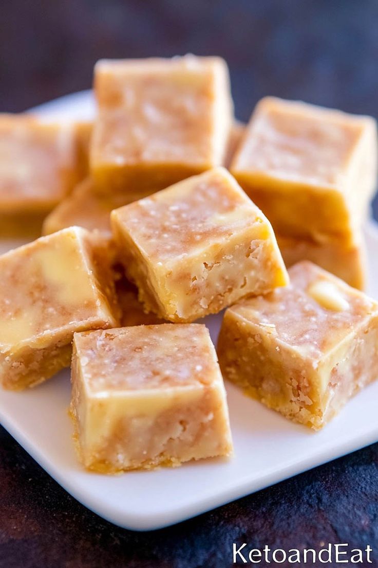 several pieces of peanut butter fudge sitting on a white plate with the rest of it cut into squares