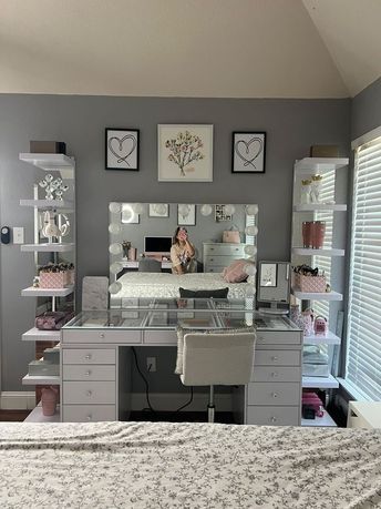 a bedroom with a bed, desk and mirror on the wall next to it's windows