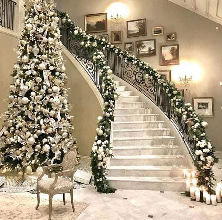 a staircase decorated with white flowers and greenery next to a christmas tree on the floor