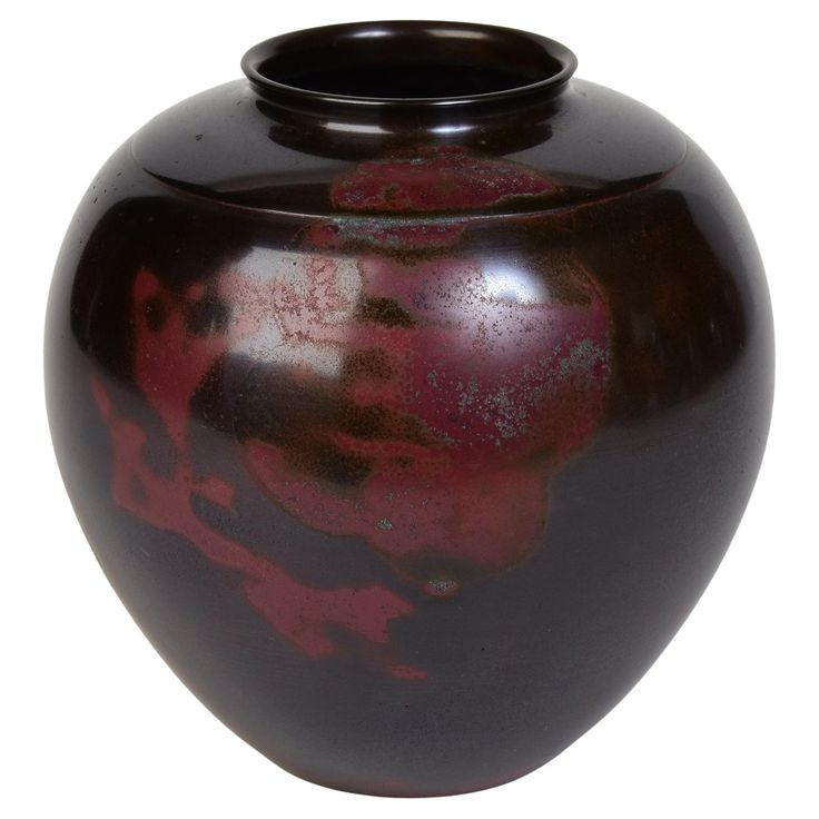 a brown and red vase sitting on top of a white table