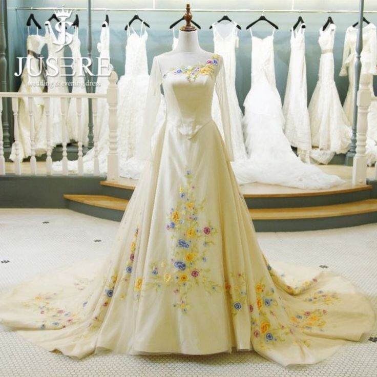 a wedding dress on display in front of a rack with dresses and gowns behind it