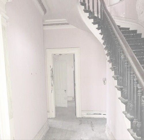 an empty hallway with white walls and stairs