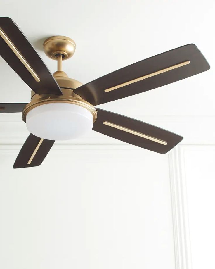 a ceiling fan that is hanging from the ceiling in a room with white walls and wood trimmings