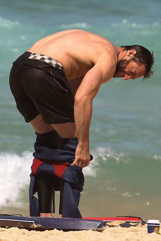 a man standing on top of a surfboard next to the ocean with his head down