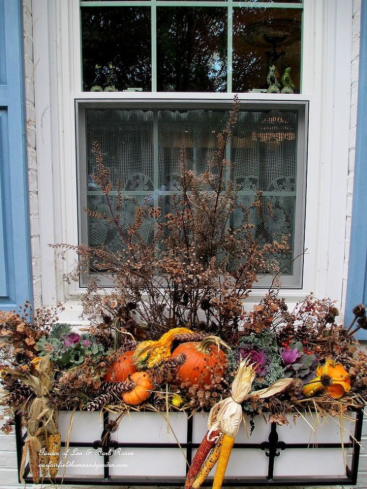 a window sill filled with lots of fake pumpkins and other autumn decorations in front of a blue door