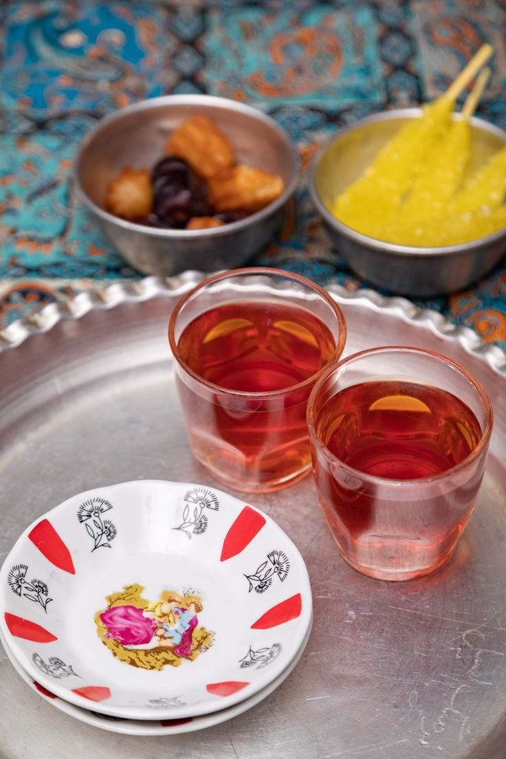 three glasses filled with tea sitting on top of a silver tray