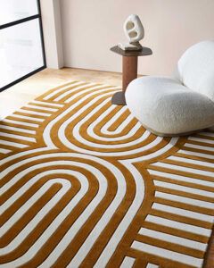 a living room with an orange and white rug on top of the floor next to a window