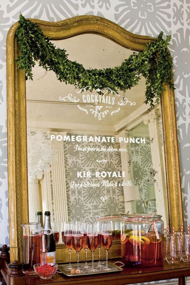 a table topped with lots of glasses filled with liquid next to a wall mounted mirror