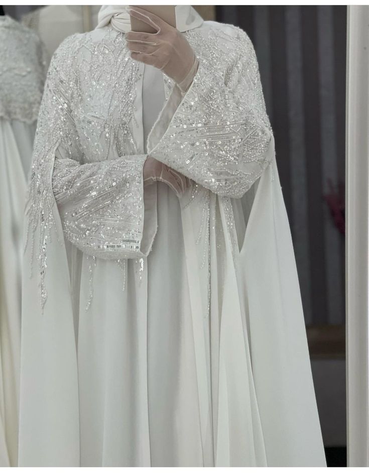 a white dress with sequins on the shoulders and sleeves is displayed in front of a mirror