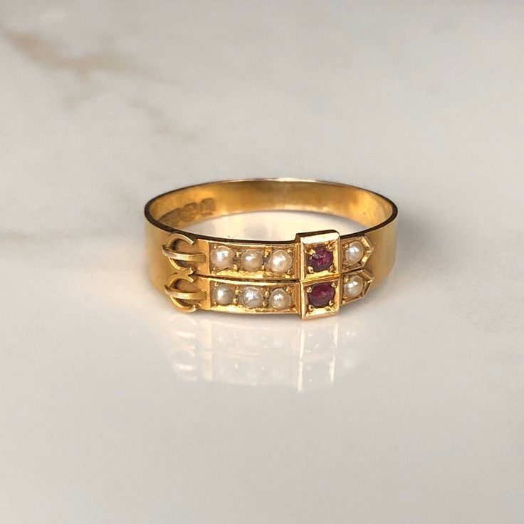 An antique 15 carat gold ring circa.1896 displaying a a collection of pearls Rubies on a buckle design. The fancy design of the setting really frames the stones perfectly. What an unusual antique! CONDITION: Wear consistent with age and use. Please see photos for more detail. FRONT SETTING: 6mm BAND WIDTH (NARROWEST): 3mm RUBY DIAMETER: 2mm PEARL DIAMETER: 2mm RING SIZE: UK: U | US: 10 1/4 WEIGHT: 3.0 grams (TTZ) Ruby And Pearl, Fancy Design, Buckle Ring, 22 Carat Gold, Platinum Diamond Rings, Red Band, Feb 8, Ring Photos, Opal Rings