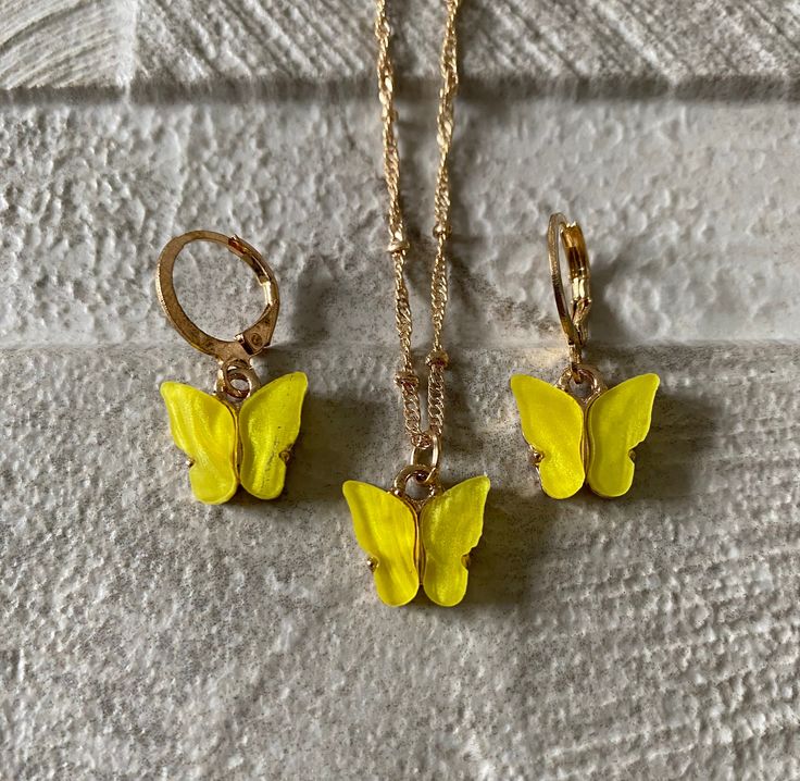 Yellow gold butterfly earrings and necklace set, small butterfly hoop and pendant necklace set, yellow butterfly resin set When you need that little something to finish of an outfit, this beautifully handmade and handcrafted butterfly set will do that.  This set will emphasise your outfit to look simple, delicate and elegant. Please note chains may vary due to stock as they are handmade.  Description:  * Gold / Yellow * 2.5cm - 1.5cm (Earring - 3.5g) estimate * 45cm - 60cm (Chain - 5g) estimate * 2.5 - 1.5cm (Pendant) estimate  * Zinc alloy / Gold finish / yellow coloured resin The necklace set is super light weight.  Beautiful accessory to make any outfit look outstandingly beautiful. The ideal gift for friends, family or even yourself.  Handmade and finished with a high standard. Each pi Yellow Jewelry With Butterfly Charm For Gift, Yellow Butterfly Jewelry Gift, Trendy Gold Resin Necklace, Gold Butterfly Print Jewelry For Gift, Gold Jewelry With Butterfly Print For Gift, Yellow Resin Jewelry As Gift, Yellow Resin Jewelry For Gifts, Yellow Resin Jewelry As A Gift, Yellow Resin Jewelry Gift