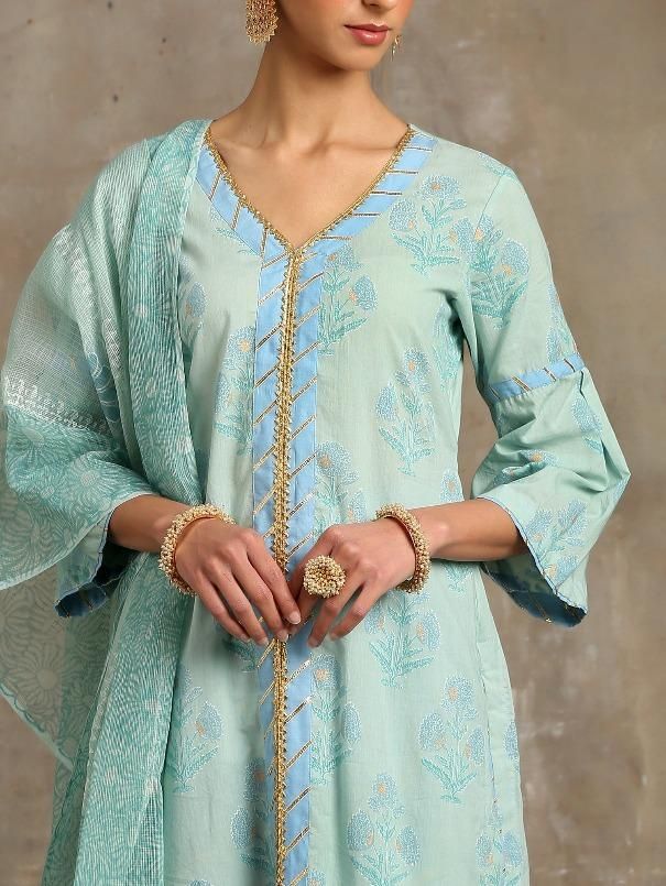 Set of 3 consists of kurta, dupatta and salwar Hand printed poppies in white and gold khari set on a sea green base. Straight v neck, bell sleeve kurta in cotton with hand-made magzi and gota detailing. Salwar - Cotton salwar set in a contrast blue with lehriya gota work Dupatta- Handwoven kota doria, block printed dupatta. Color - Turquoise Fabric - Cotton and Kota Doria Occasion - Festive Wear / Bridal Wear Fit - Straight, Relaxed and Comfortable Pattern - Printed Care - Dry Clean only Estimat Turquoise Fabric, Salwar Suits, Hip Length, Festival Wear, Bridal Wear, Length Sleeve, Bell Sleeves, Tunic Tops, Perfect Fit