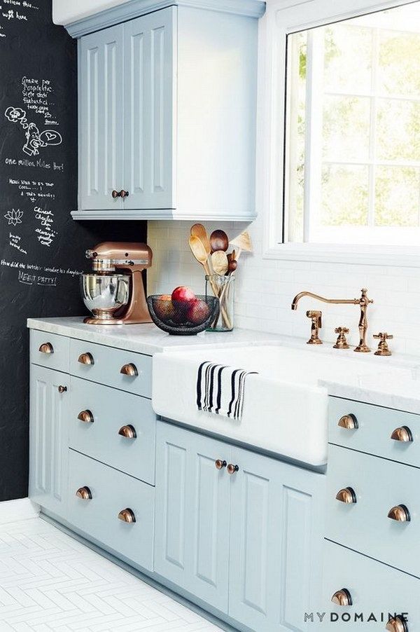 a kitchen with blue cabinets and white countertops has a chalkboard on the wall