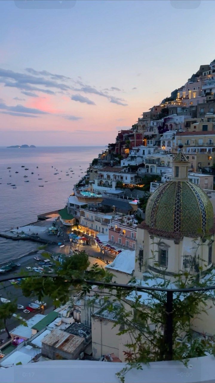 a view of the ocean and buildings at dusk from an apartment building in positi, italy