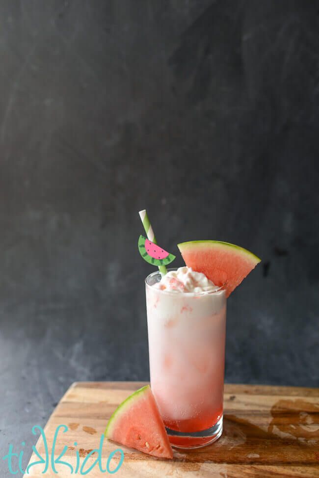 a watermelon drink is garnished with whipped cream and a green leaf