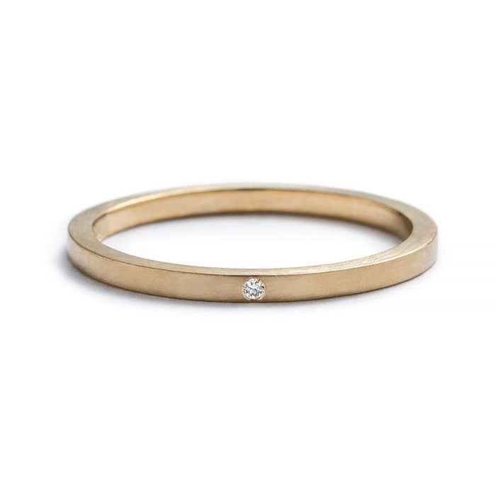 a gold wedding band with a single diamond in the center, on a white background