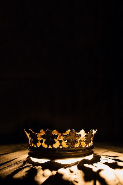 a crown sitting on top of a wooden table next to a light shining through it