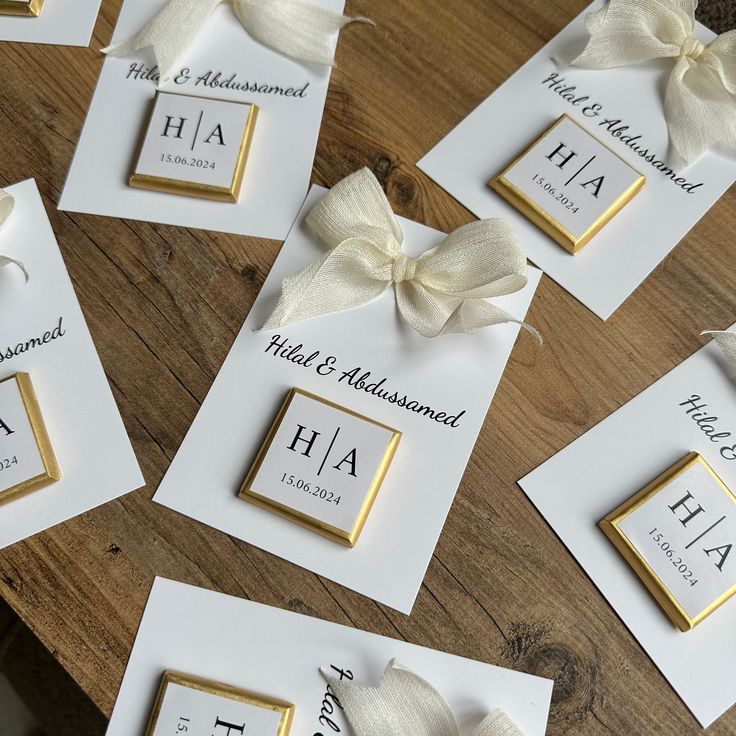 wedding place cards with white bows and gold trim on wooden table top for guests to sign