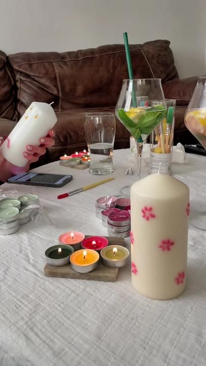 a woman sitting at a table with candles and other items on the table in front of her