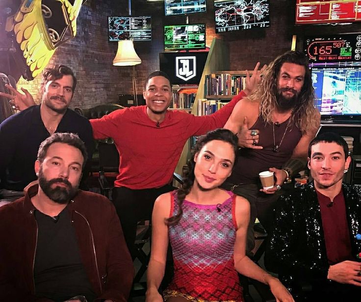 a group of men and women posing for a photo in front of a tv screen