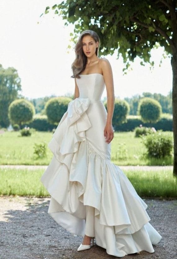 a woman in a white wedding dress standing next to a tree