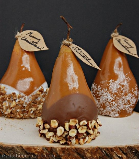 three pears with some nuts on top of them and one has a sign that says caramel dipped pears