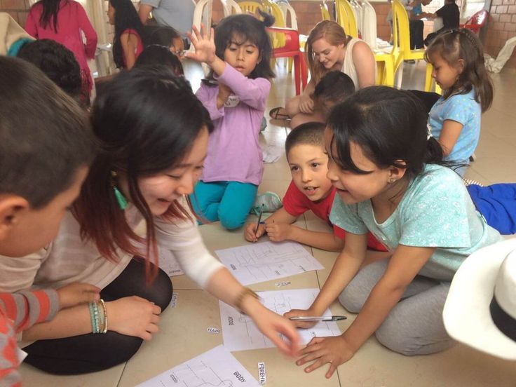 a group of children sitting on the floor looking at papers with scissors in their hands