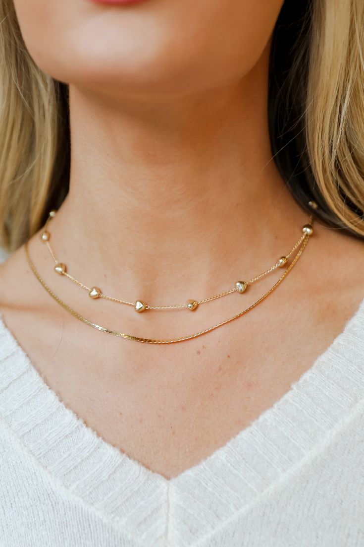 Showcase your sweeter side when you wear the Aria Gold Heart Layered Chain Necklace! This trendy necklace features two layers of gold chains with hearts. Style the Aria Necklace with any outfit to instantly upgrade your look! Gold Plated Layered Hearts Lobster Clasp with Extender Layer 1 | Length 7" Layer 2 | Length 6.5" Extender | Length 3" Trendy Gold Heart Necklace With Adjustable Chain, Trendy Double Chain Heart Necklace, Gold Heart-shaped Layered Necklace With Clavicle Chain, Trendy Heart-shaped Double Chain Necklace, Trendy Heart Shaped Double Chain Jewelry, Trendy Heart-shaped Double Chain Jewelry, Gold Heart Pendant Layered Necklace, Gold Layered Heart Pendant Necklace, Gold Heart Pendant Necklace For Layering