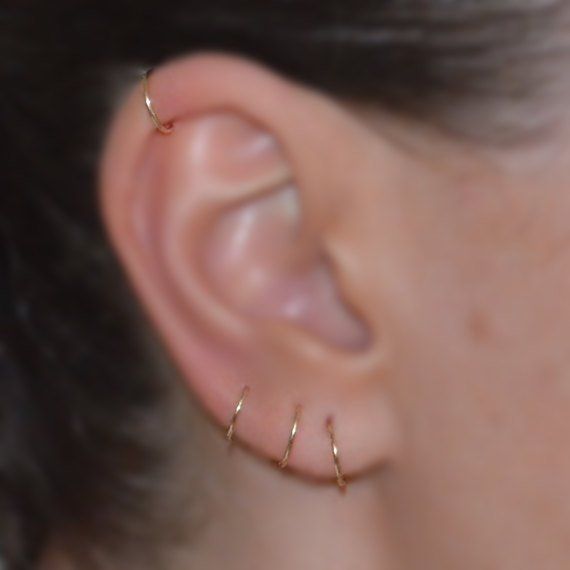 a close up view of a person's ear with two small silver hoops