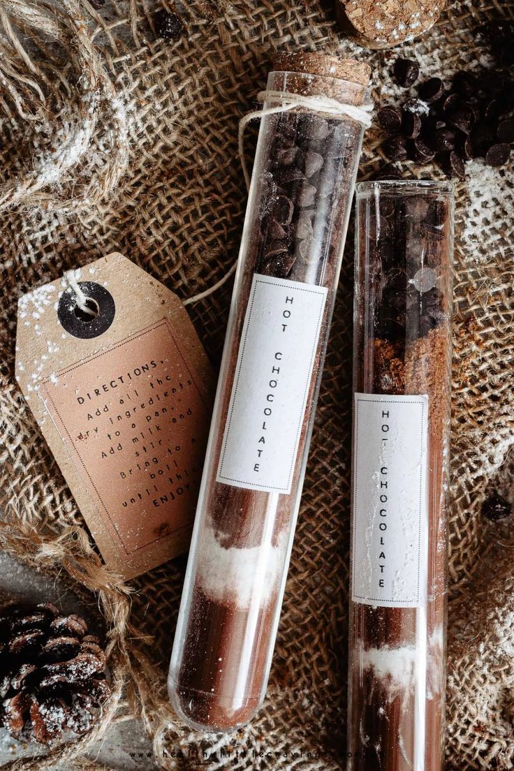 two tubes filled with chocolate and cocoa on top of a burlick bag next to a pine cone